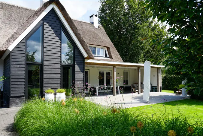 Foto van moderne woning met gekeimd metselwerk en een houten accent en rieten kap